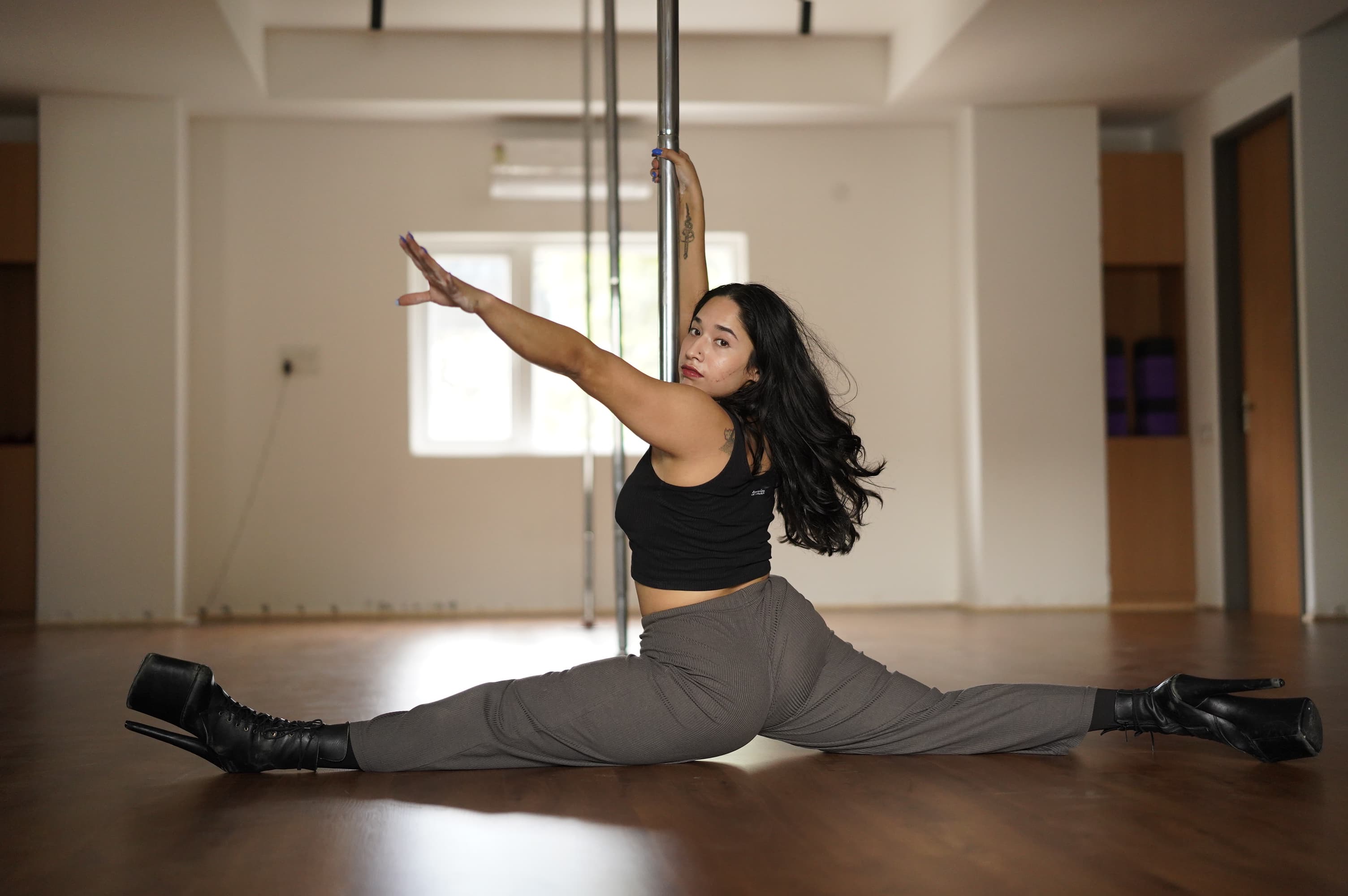 Azdah in a full split holding the pole